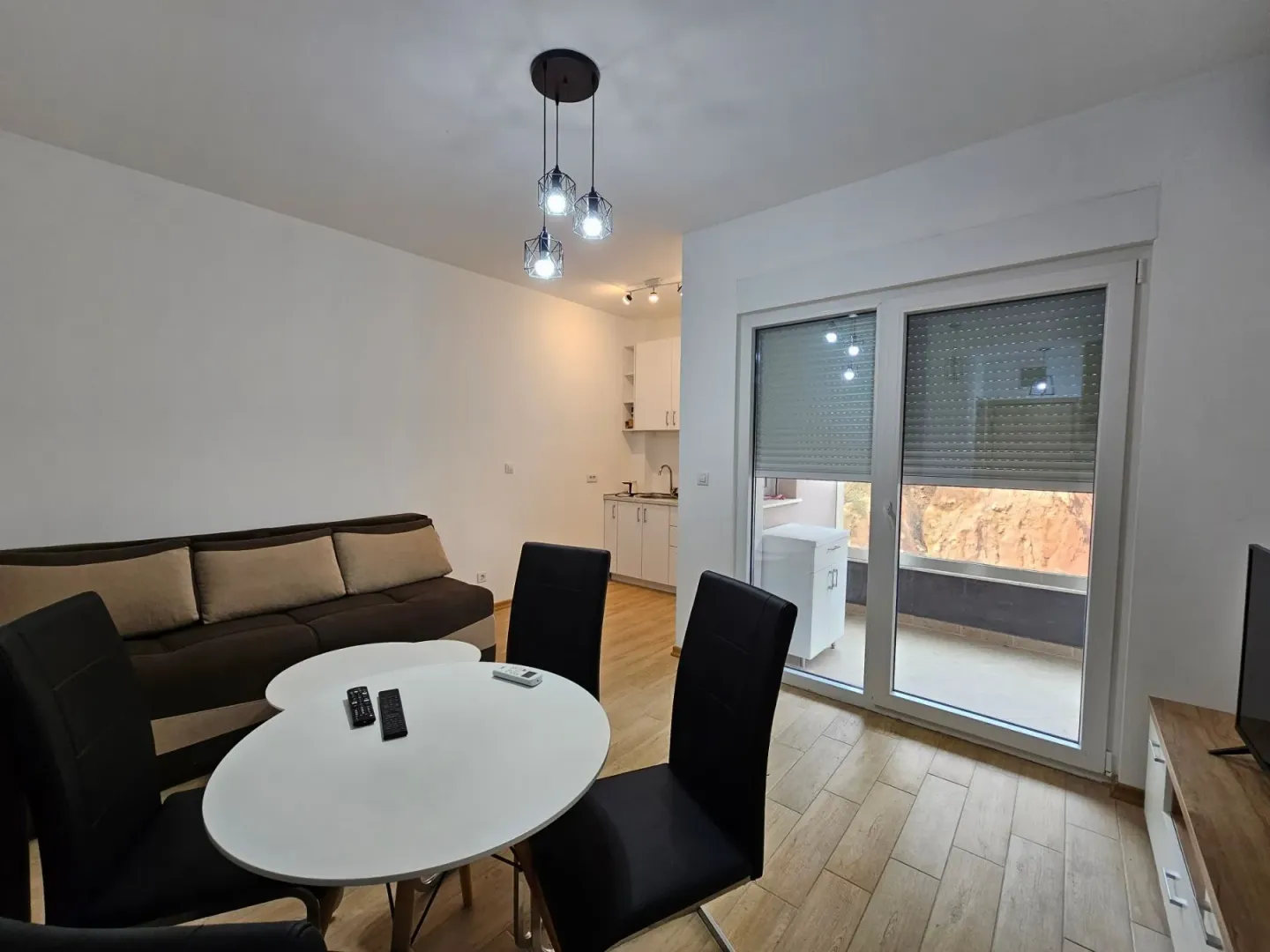 Living room with a sofa, dining table, and access to the terrace.