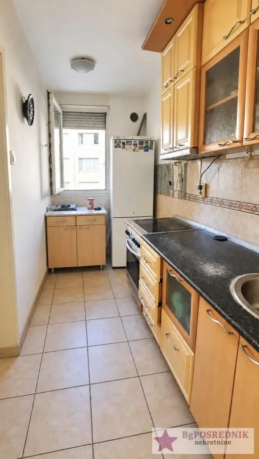 Long kitchen with wooden cabinets and a built-in refrigerator.