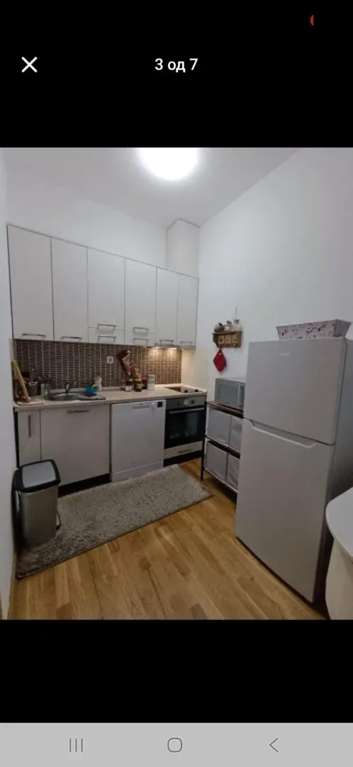Small equipped kitchen with white cabinets and appliances.