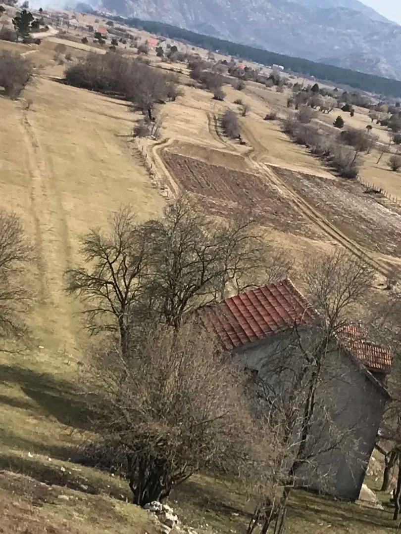 Pogled iz vazduha na seosko imanje sa starom kućom i poljoprivrednim zemljištem.