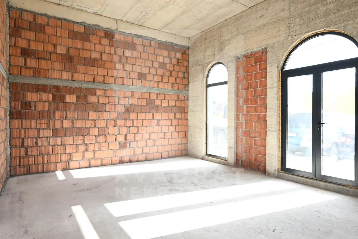 Unfinished room under construction with brick walls and large windows.