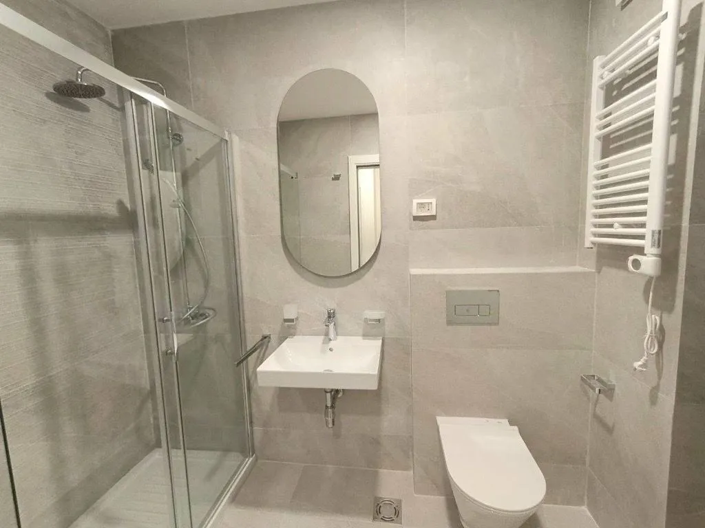 Moderno opremljeno kupatilo sa tuš kabinom, umivaonikom i WC šoljom.