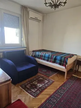 Manja spavaća soba sa krevetom, foteljom i parketom na podu. - image 4