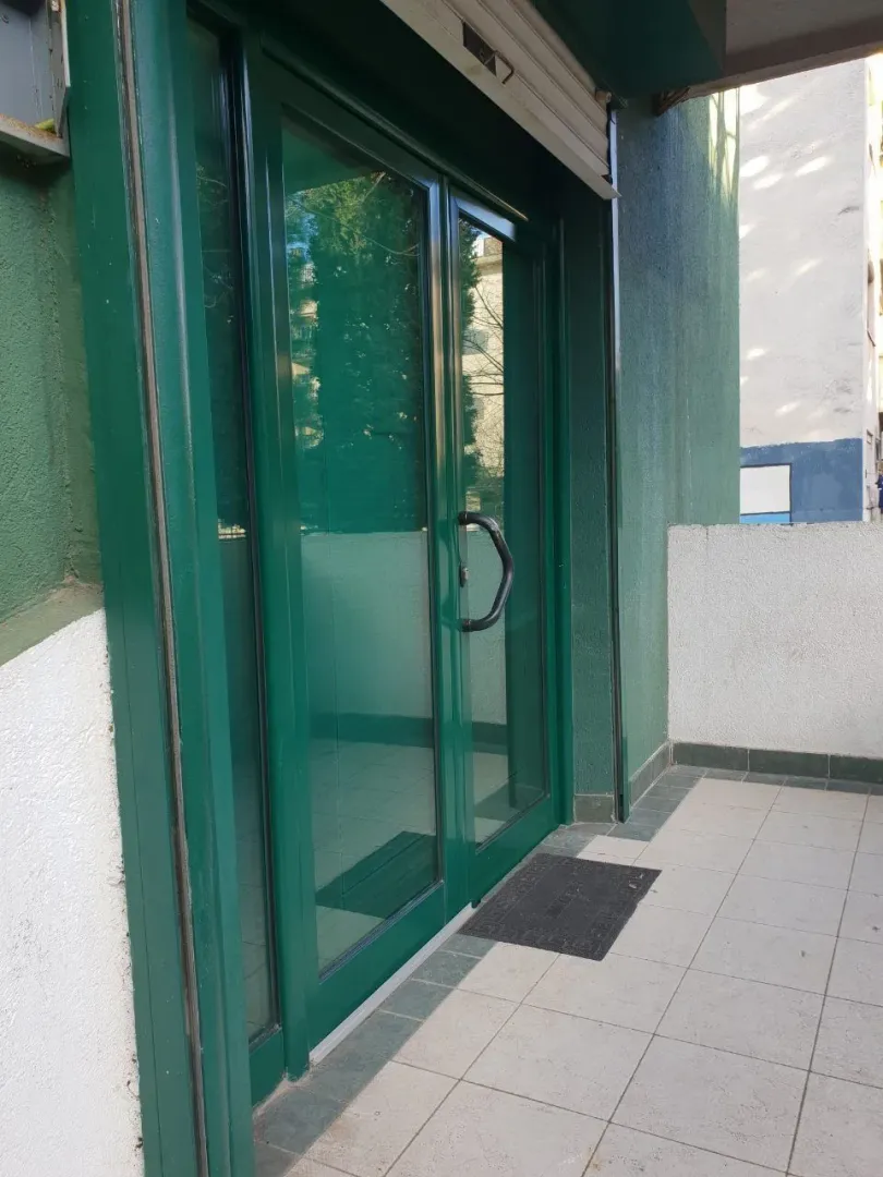 Green glass entrance door viewed from the terrace.
