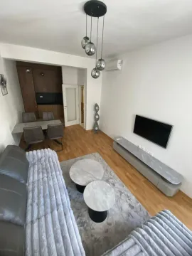 Living room with a sofa, dining area, and a fitted kitchen in the background. - image 7