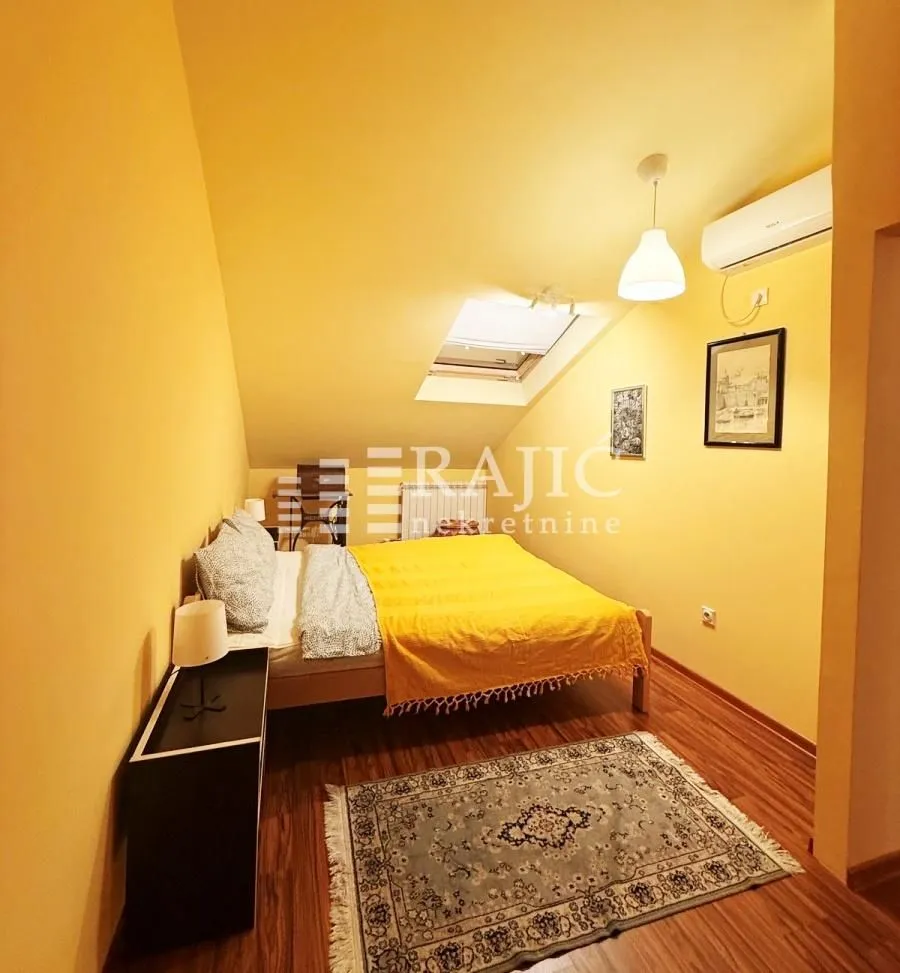 Attic bedroom with a double bed, yellow walls, and a roof window.