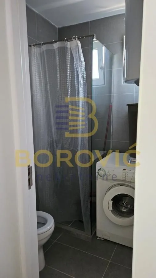 Smaller bathroom with a shower cabin and a washing machine.