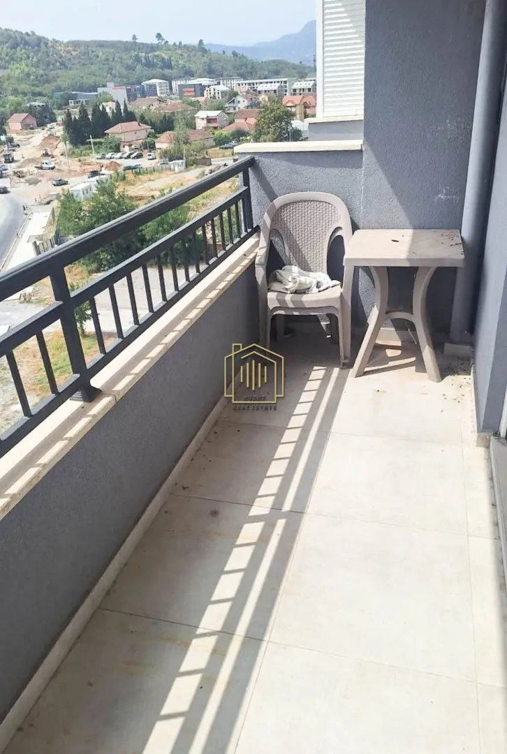 Small balcony with a table and chair and a view of the surroundings.