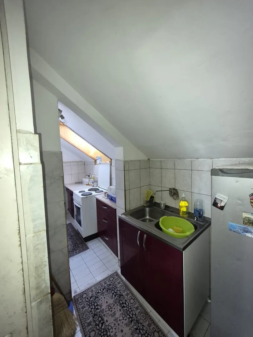 Manja kuhinja sa sudoperom, elementima i šporetom u potkrovlju.