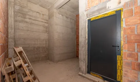 Unfinished room under construction with an entrance door and wooden pallets. - image 4