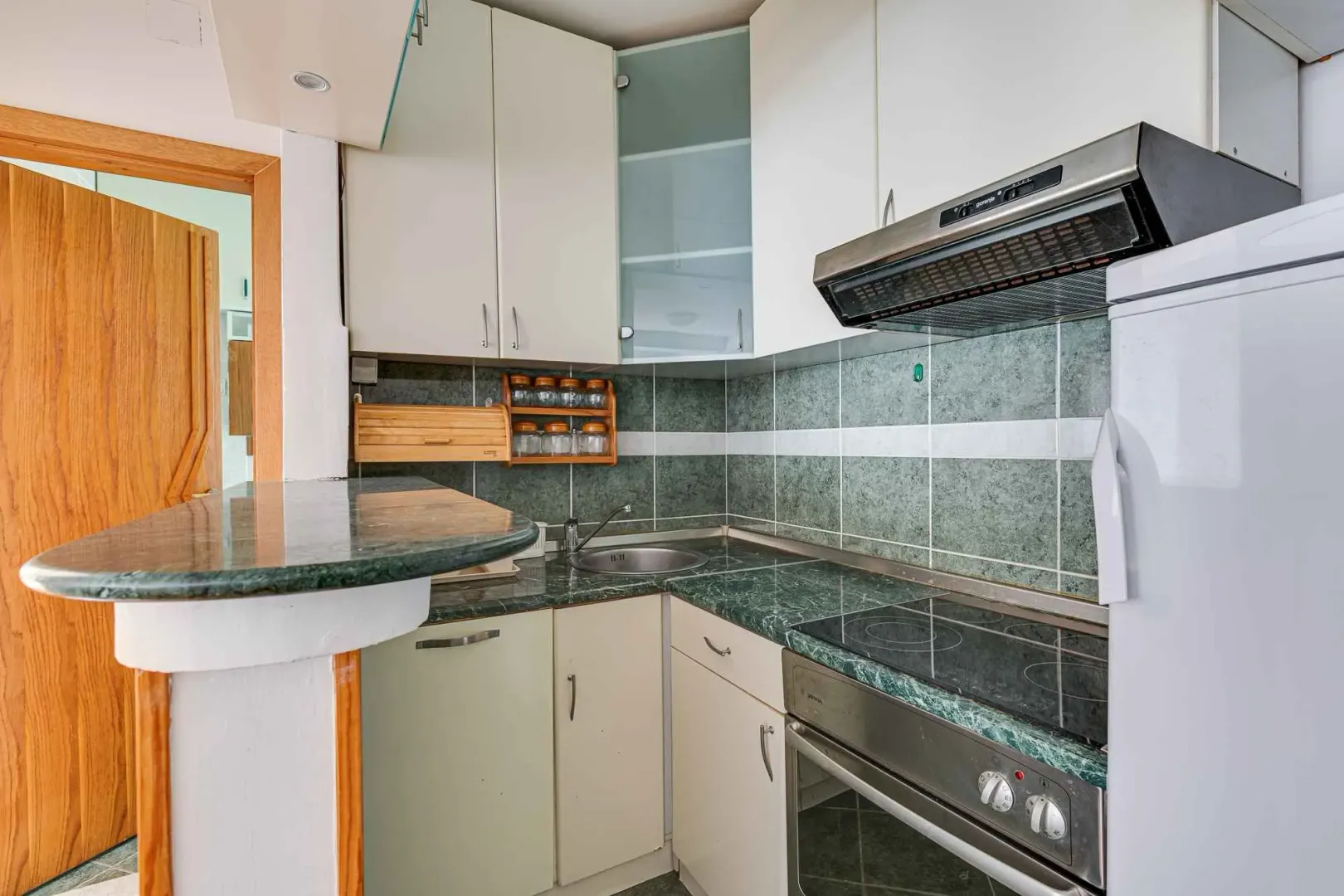 Compact equipped kitchen with white cabinets and marble countertop.