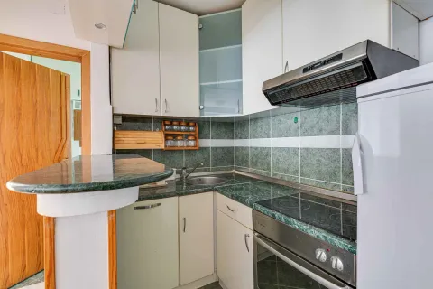 Compact equipped kitchen with white cabinets and marble countertop. - image 13