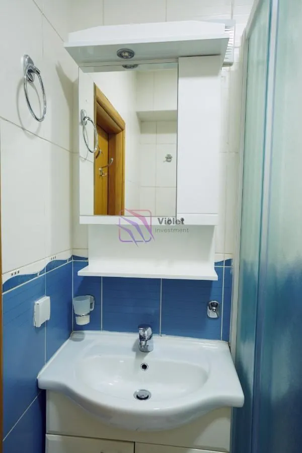 Small bathroom with a washbasin, mirror, and white cabinet.
