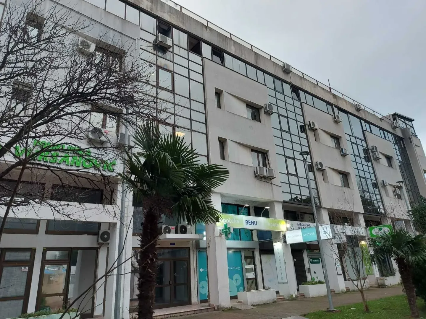 Exterior view of a multi-story building with commercial spaces on the ground floor.
