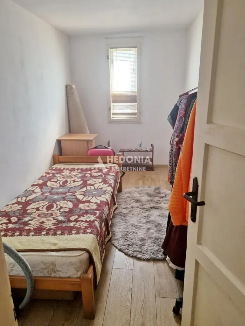 Manja spavaća soba sa krevetom i prozorom.