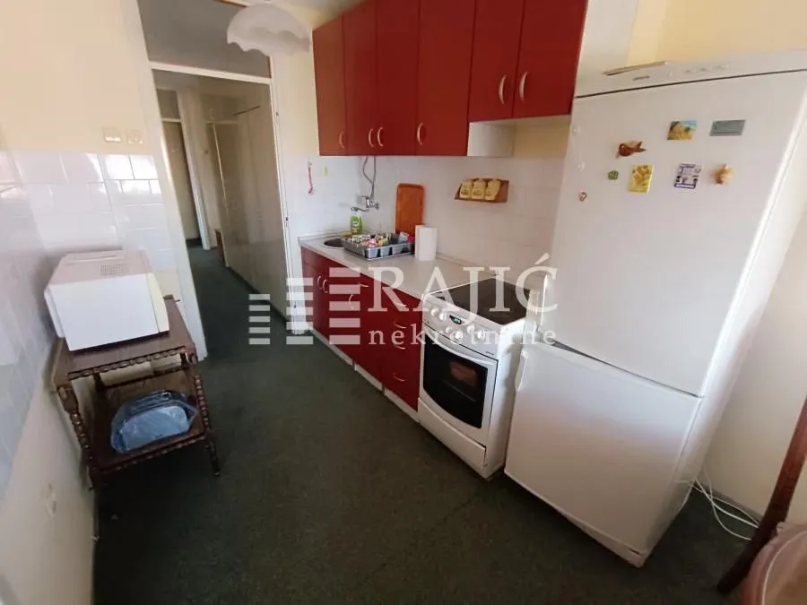 Small kitchen with red cabinets and a white refrigerator.