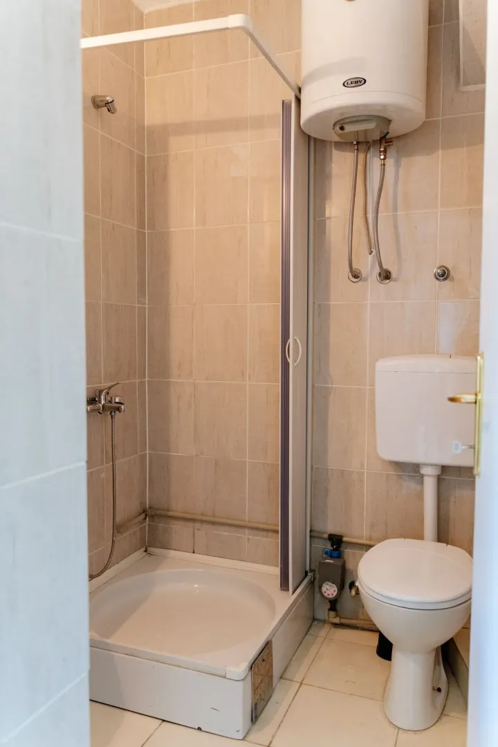 A simple bathroom with a shower cabin, toilet, and water heater.