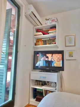 Small bedroom with a television, bookshelves, and an air conditioning unit. - image 7