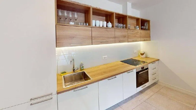 Moderna kuhinja sa drvenim elementima, sudoperom i ugrađenom rernom.