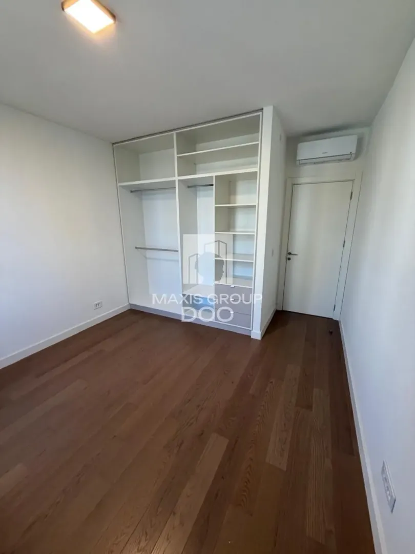 Spavaća soba sa ugradnim ormarom i drvenim podom.