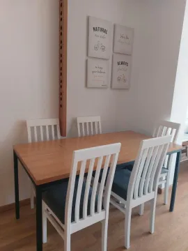 Dining area with a wooden table and white chairs. - image 19