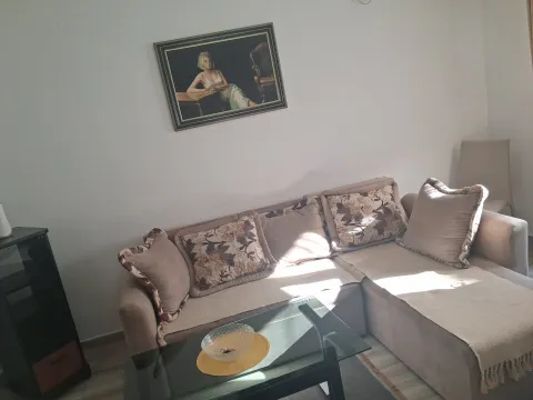 Living room with a sectional sofa, coffee table, and a painting on the wall. - image 7