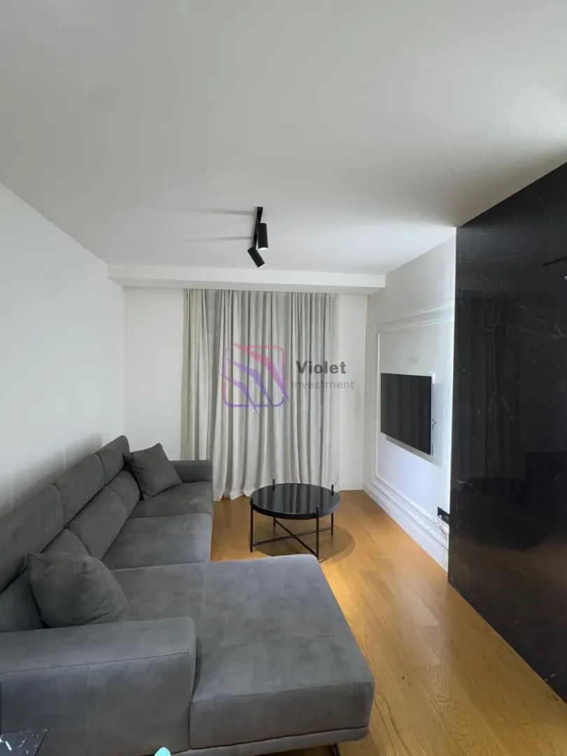 Living room with a sectional sofa, coffee table, and wall-mounted TV.