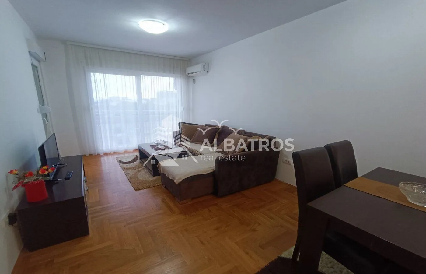 Living room with a sofa, TV unit, and dining table.