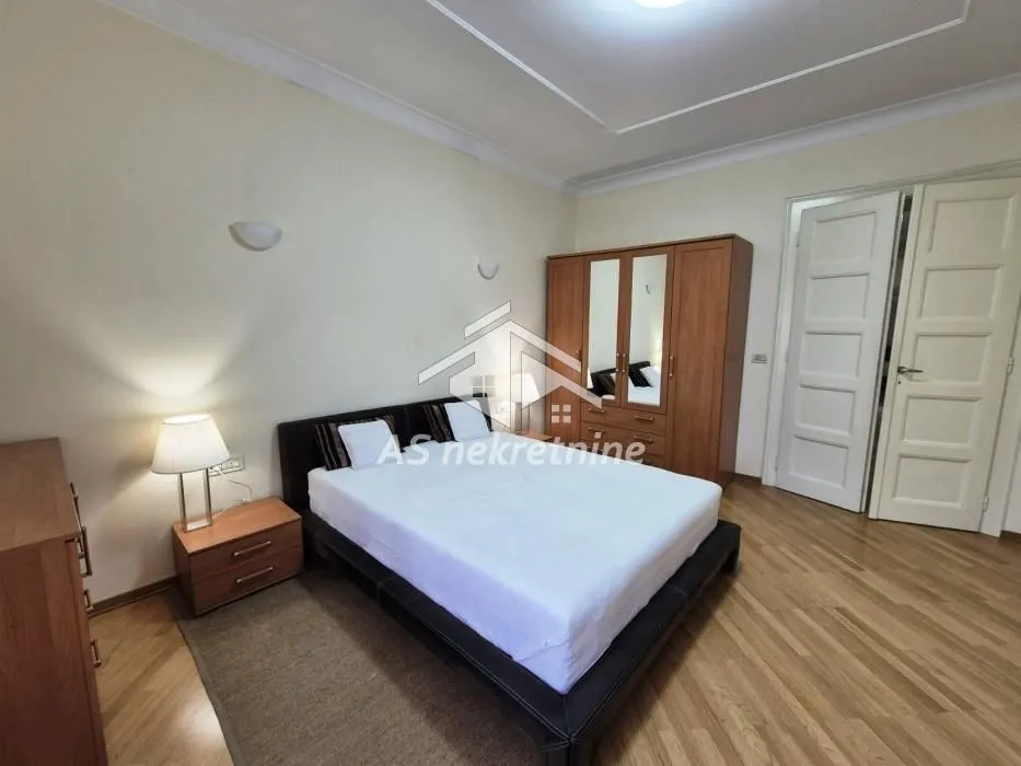 Spacious bedroom with a double bed, wooden wardrobe, and laminate flooring.