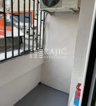Small covered balcony with protective railing and an air conditioning unit. - image 5