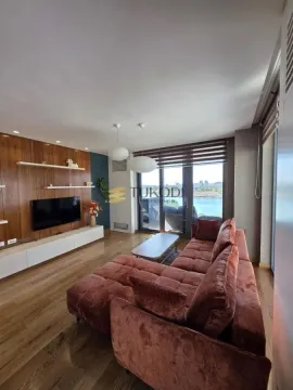 Living room with a comfortable sectional sofa, wooden wall panels, and a river view. - image 2