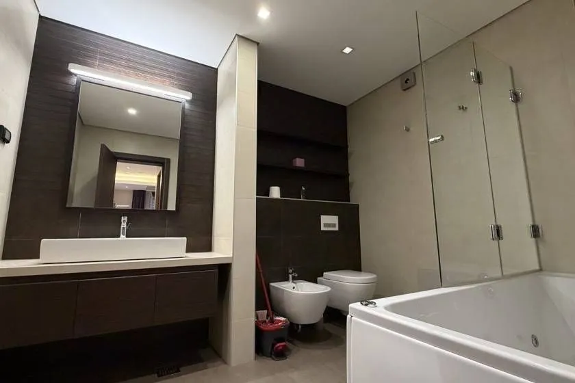 Modern bathroom with a sink, toilet, bidet, and a bathtub with a glass screen.