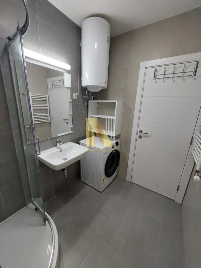 Moderno opremljeno kupatilo sa tuš kabinom, umivaonikom i veš mašinom.