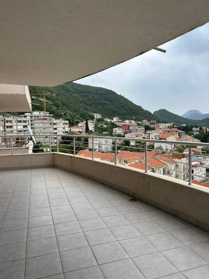 Prostrana popločana terasa sa pogledom na grad i brda.