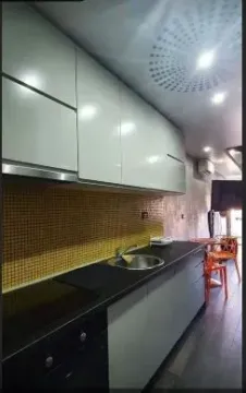 Moderna kuhinja sa tamnim radnim površinama i žutim mozaik pločicama. - image 2