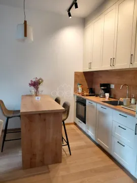 Moderna kuhinja sa bijelim elementima i trpezarijskim stolom sa barskim stolicama. - image 3