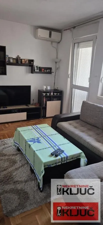 Dnevna soba sa garniturom, TV-om i izlazom na terasu.