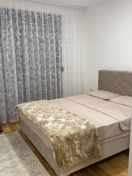 A furnished bedroom with a double bed and a large window with curtains. - image 3