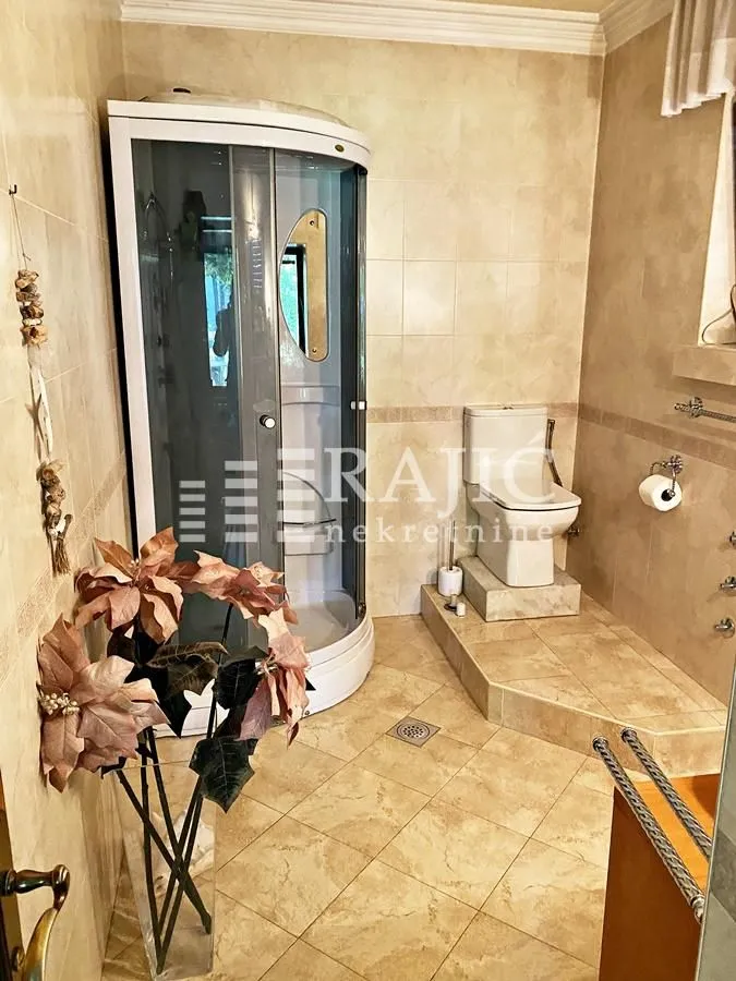 Tiled bathroom with a shower cabin and toilet.