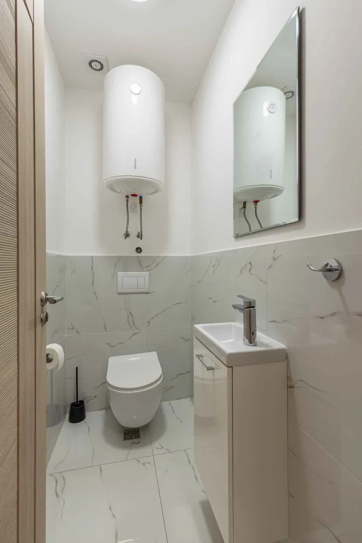 Manje kupatilo sa WC šoljom, umivaonikom i bojlerom.