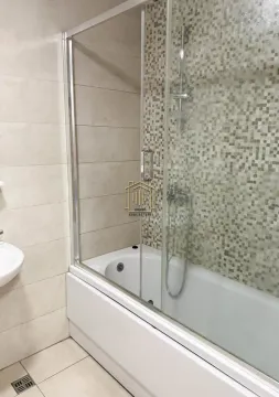 Bathroom with a bathtub and a glass screen. - image 6