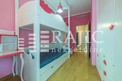 Children's bedroom with bunk beds and a wardrobe in pink and white tones.