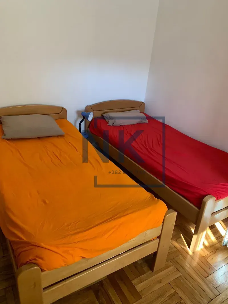 Bedroom with two wooden beds with orange and red bedding.
