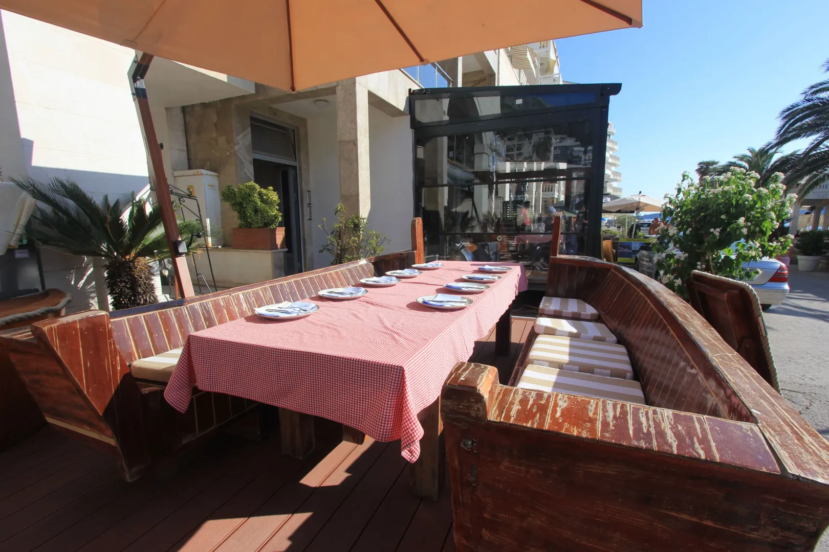 Terrace with a wooden table and benches covered with a tablecloth outdoors.