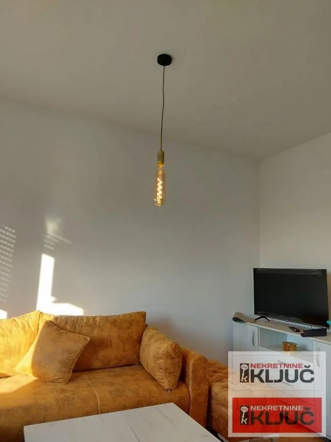 Dnevna soba sa žutom garniturom i televizorom.