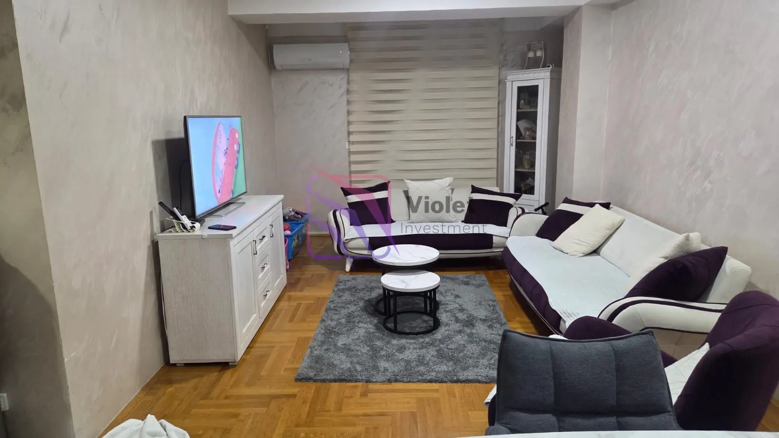 Dnevna soba sa garniturom, stočićem i televizorom.