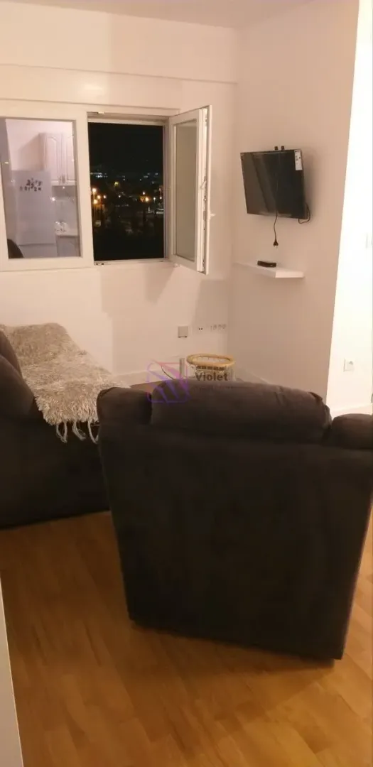 Small living room with a sofa set and a wall-mounted TV.