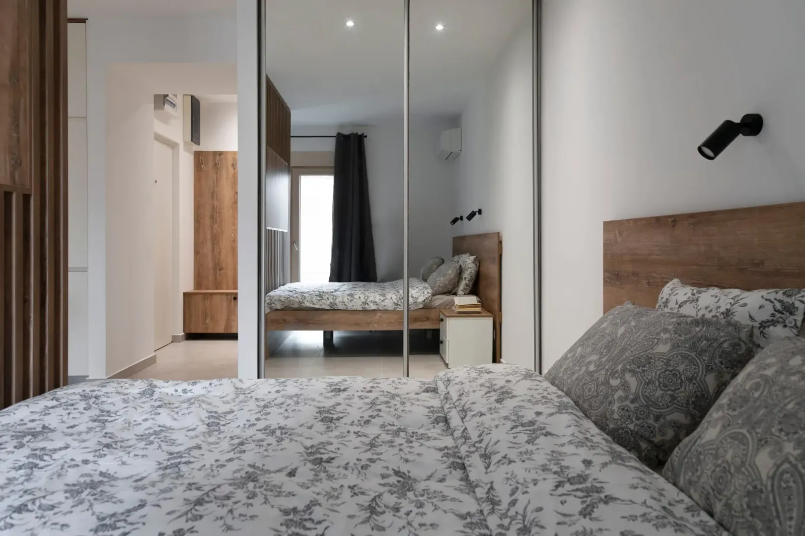 Modern bedroom with a double bed and a large built-in mirrored wardrobe.