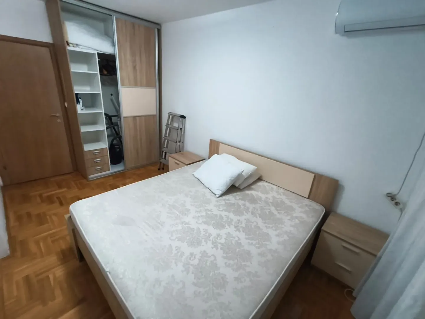Bedroom with a double bed, wardrobe, and wooden flooring.