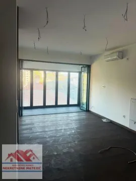 Prazna soba sa tamnim drvenim podom i staklenim vratima prema terasi. - image 25